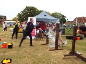 man throwing bucket of water over man in stocks