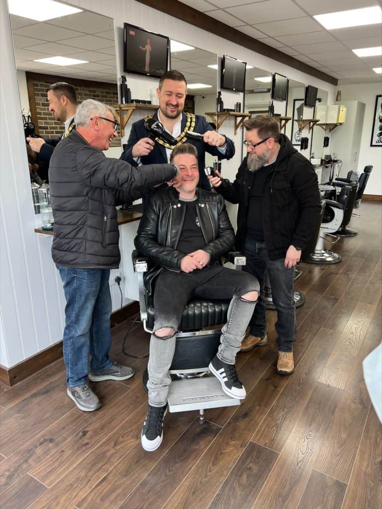 Man in barbering chair with friends and family