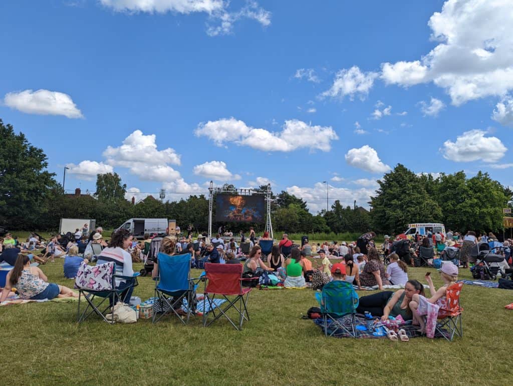 Group of people in field at family fun day watching open air cinema