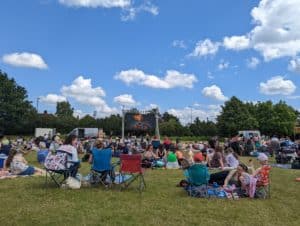 Group of people in field at family fun day watching open air cinema