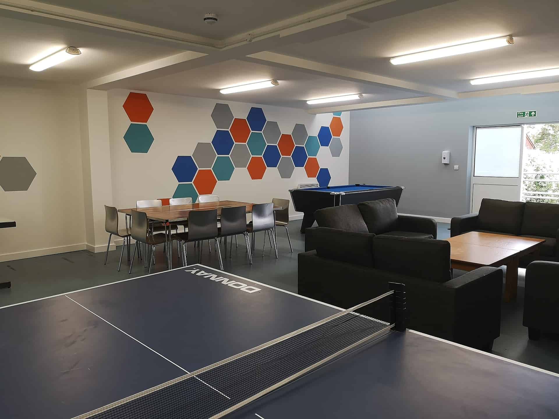 Colourful wall with blue table tennis table and sofas in the hub