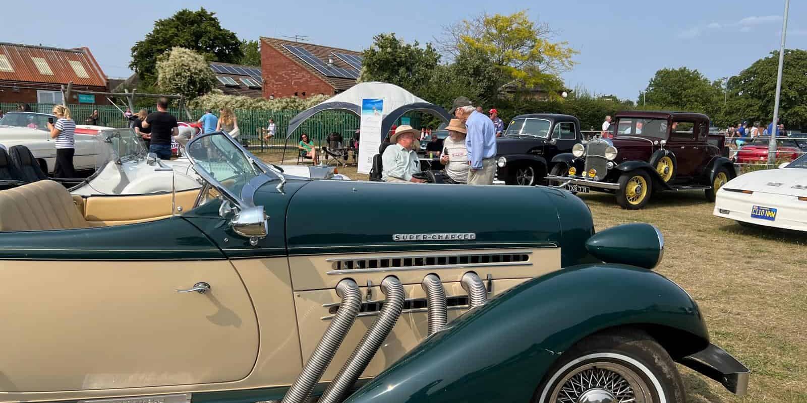 cream and green vintage car with people looking at it